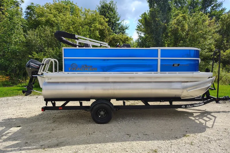 The Image of 2027 Sun Tracker Party Barge 16 DLX pontoon boat on trailer, parked outdoors. - 0