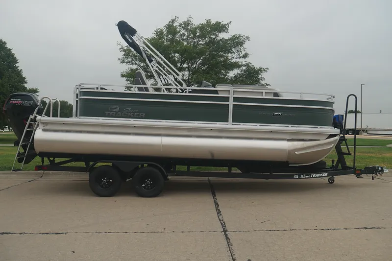 The Image of 2027 Sun Tracker Fishin' Barge 20 DLX pontoon boat on trailer, parked outdoors. - 0