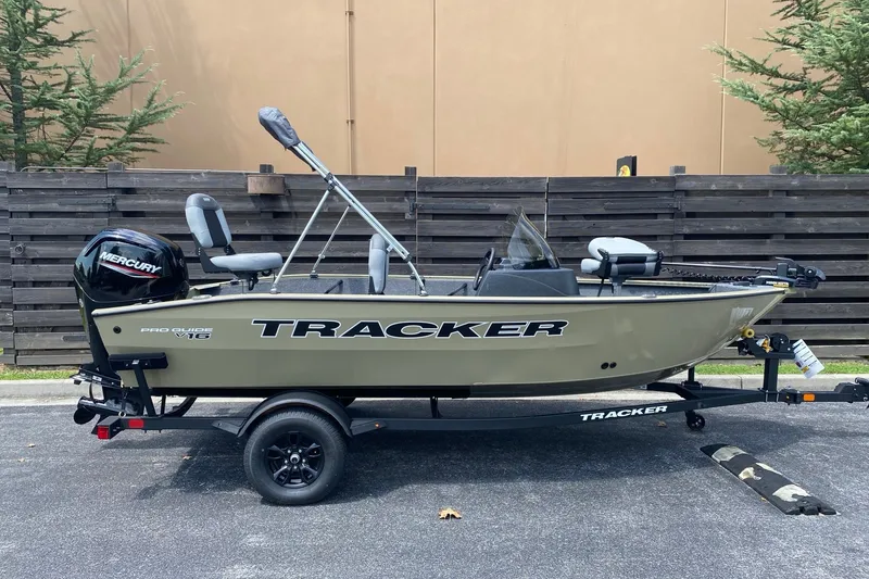 The Image of 2027 Tracker Pro Guide V-16 SC boat on trailer, parked outdoors. - 0