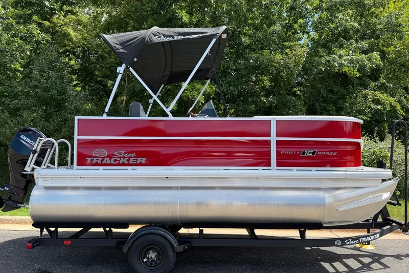 The Image of 2027 Sun Tracker Party Barge 16 DLX pontoon boat on trailer, parked outdoors. - 0