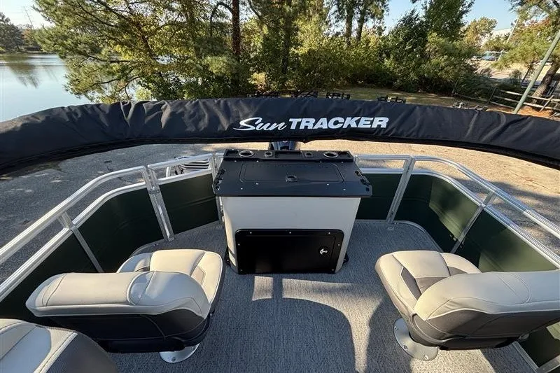 Slide: The Image of 2027 Sun Tracker Fishin' Barge 20 DLX interior with seating and console, near a lake. - 31