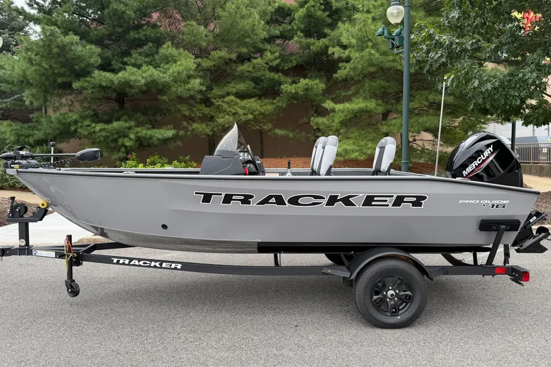 The Image of 2027 Tracker Pro Guide V-16 SC fishing boat on trailer, parked outdoors. - 0