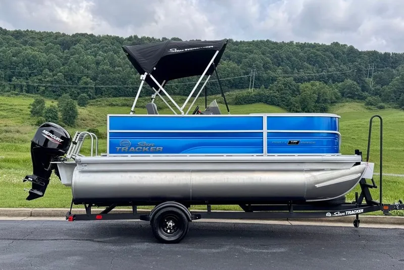 The Image of 2027 Sun Tracker Party Barge 16 DLX pontoon boat on trailer, scenic background. - 0