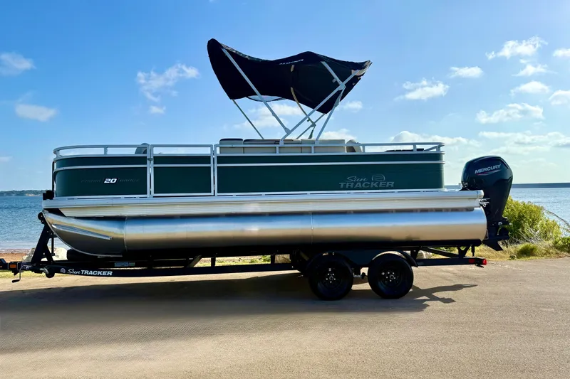 Slide: The Image of 2027 Sun Tracker Fishin' Barge 20 DLX pontoon boat on trailer by the water. - 18