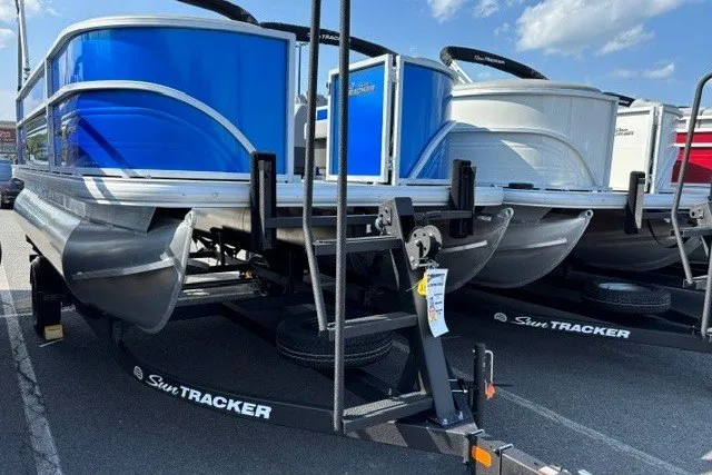 The Image of 2027 Sun Tracker Party Barge 16 DLX pontoon boats on trailers, parked under a clear sky. - 0
