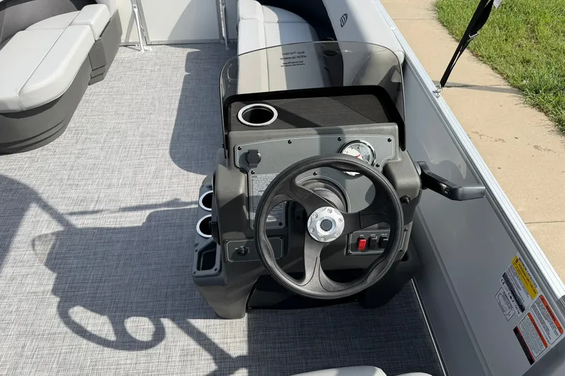 Slide: The Image of 2027 Sun Tracker Party Barge 16 DLX steering console with cup holders and seating. - 17