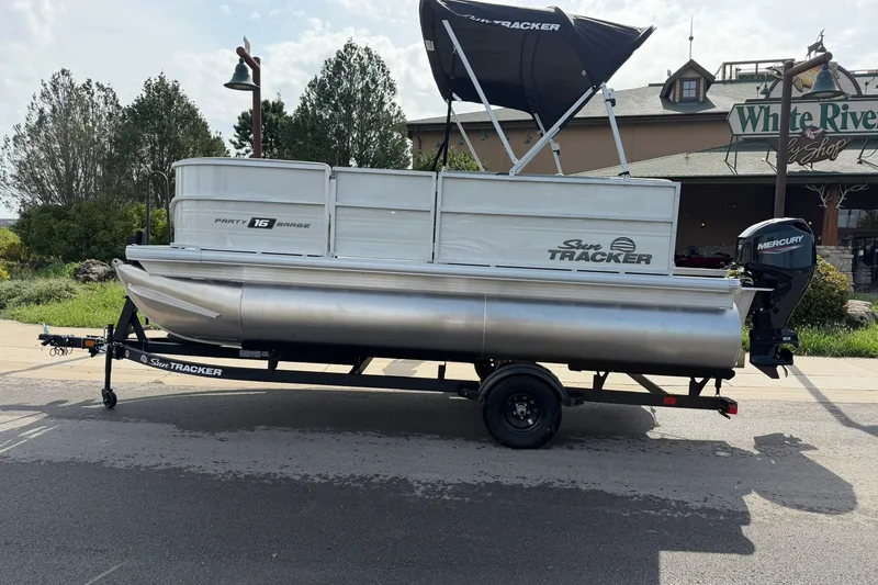 The Image of 2027 Sun Tracker Party Barge 16 DLX pontoon boat on trailer, parked outdoors. - 0