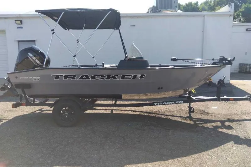 The Image of 2027 Tracker Pro Guide V-16 SC boat on trailer, parked outdoors. - 0