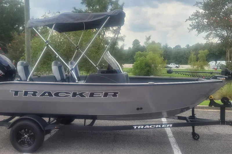 The Image of Ein graues Tracker-Boot, Modell Pro Guide V-16 SC, steht auf einem Anhänger in einem Parkplatz. - 0