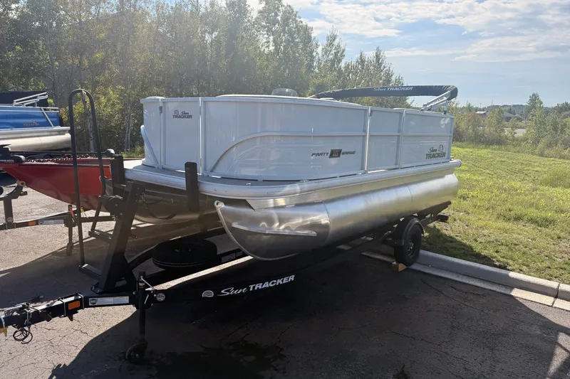 The Image of 2027 Sun Tracker Party Barge 16 DLX pontoon boat on trailer, parked outdoors. - 0