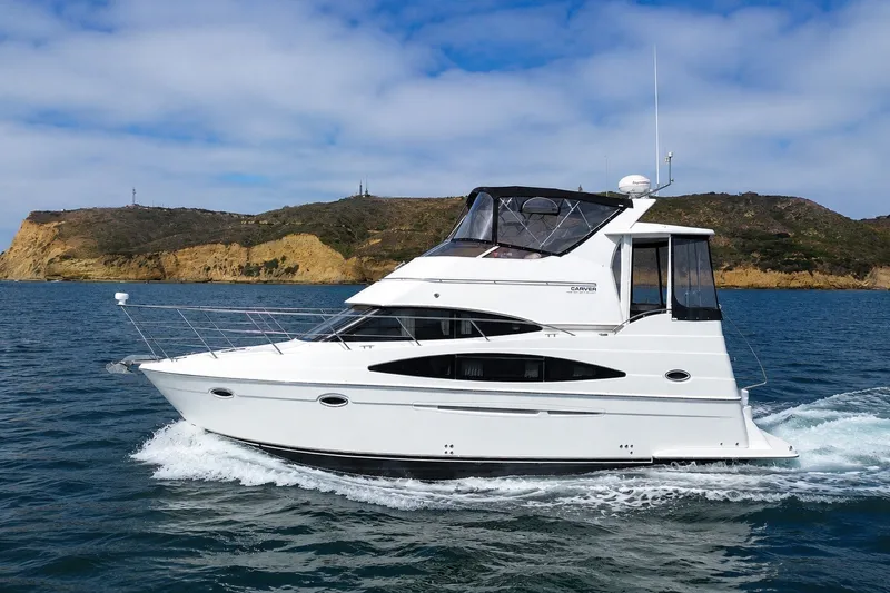 The Image of 2004 Carver 366 Motor Yacht cruising on blue ocean near rocky coastline. - 0