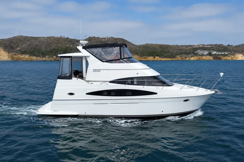 Slide: The Image of 2004 Carver 366 Motor Yacht cruising on blue water near rocky coastline. - 21