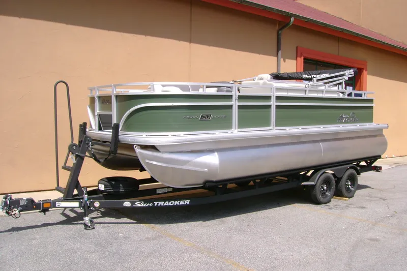 Slide: The Image of 2027 Sun Tracker Fishin' Barge 20 DLX pontoon boat on trailer, parked outdoors. - 13