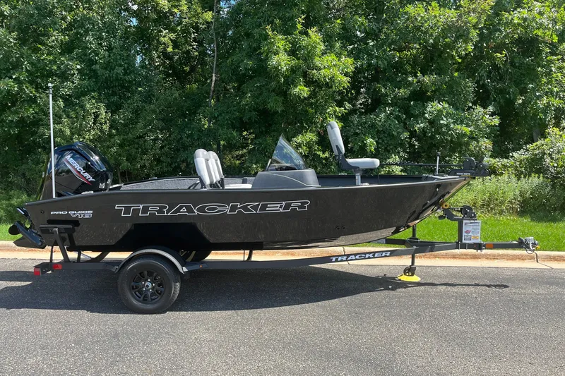 The Image of 2027 Tracker Pro Guide V-16 SC boat on trailer, parked outdoors. - 0
