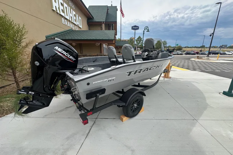 The Image of 2027 Tracker Pro Guide V-16 SC boat with Mercury engine on display outdoors. - 0