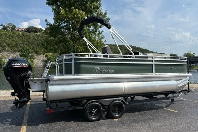 Slide: The Image of 2027 Sun Tracker Fishin' Barge 20 DLX pontoon boat on trailer, parked near a lake. - 86