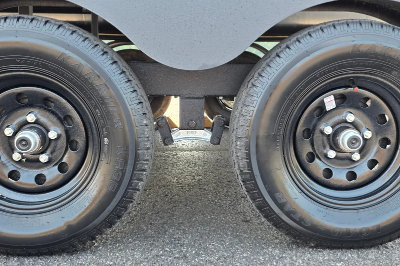 Slide: The Image of Close-up of Sun Tracker Fishin' Barge 20 DLX 2027 trailer wheels on asphalt. - 18