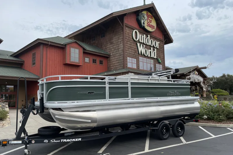 The Image of 2027 Sun Tracker Fishin' Barge 20 DLX pontoon boat outside Bass Pro Shops Outdoor World. - 0