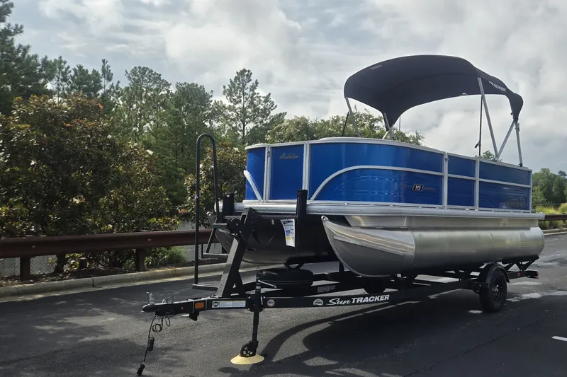 The Image of 2027 Sun Tracker Party Barge 16 DLX pontoon boat on trailer, parked outdoors. - 0