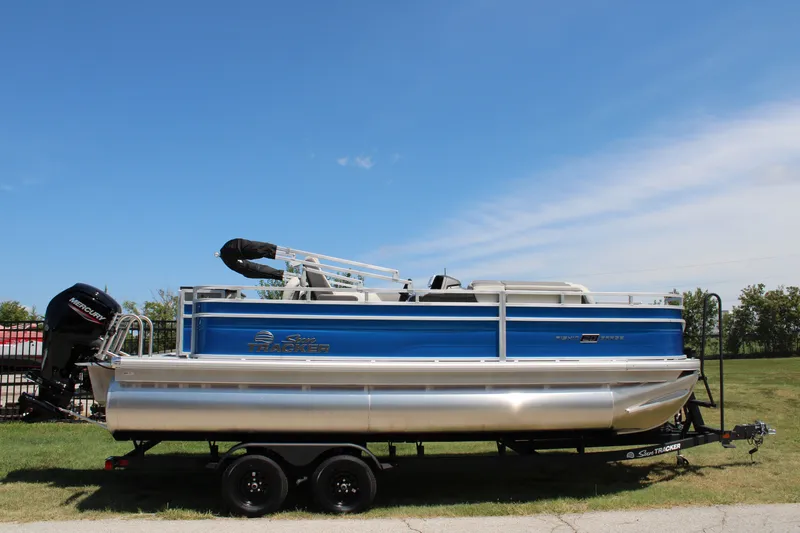 The Image of 2027 Sun Tracker Fishin' Barge 20 DLX pontoon boat on trailer, outdoors. - 0
