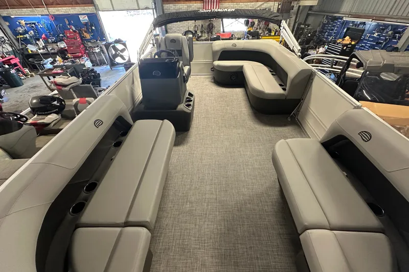 Slide: The Image of 2027 Sun Tracker Party Barge 16 DLX interior with spacious seating in a workshop setting. - 12