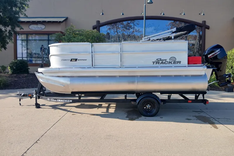 The Image of 2027 Sun Tracker Party Barge 16 DLX pontoon boat on trailer, parked outdoors. - 0