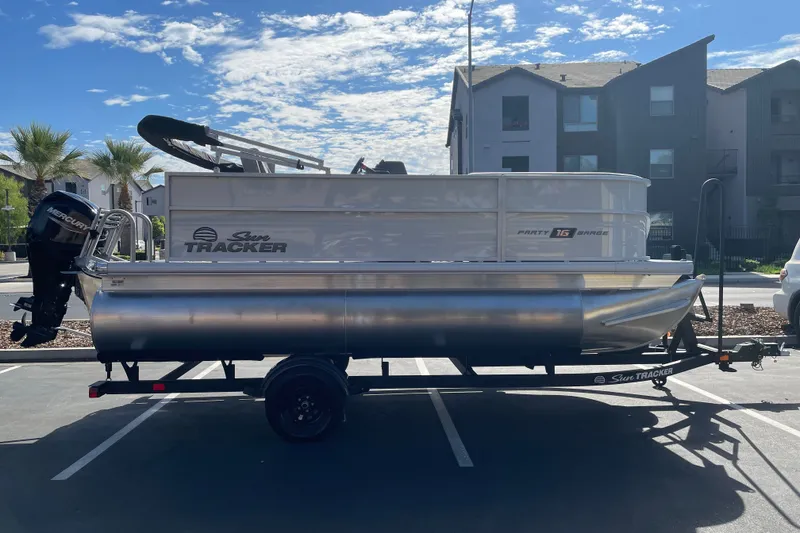 The Image of 2027 Sun Tracker Party Barge 16 DLX pontoon boat on trailer in parking lot. - 0