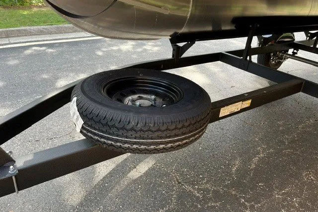 Slide: The Image of 2027 Sun Tracker Party Barge 16 DLX trailer with spare tire on asphalt road. - 12