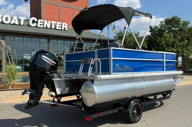 Slide: The Image of 2027 Sun Tracker Party Barge 16 DLX pontoon boat at a boat center, featuring a Mercury engine. - 13