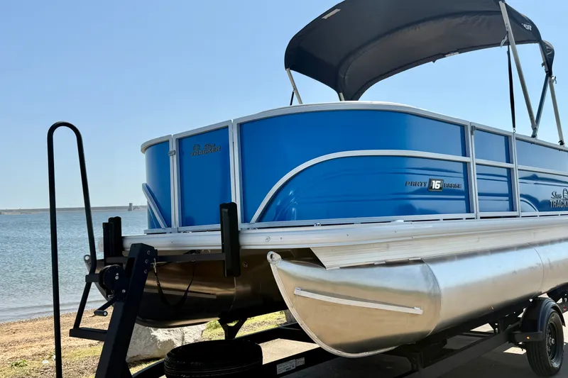 Slide: The Image of 2027 Sun Tracker Party Barge 16 DLX pontoon boat on trailer by the water. - 17