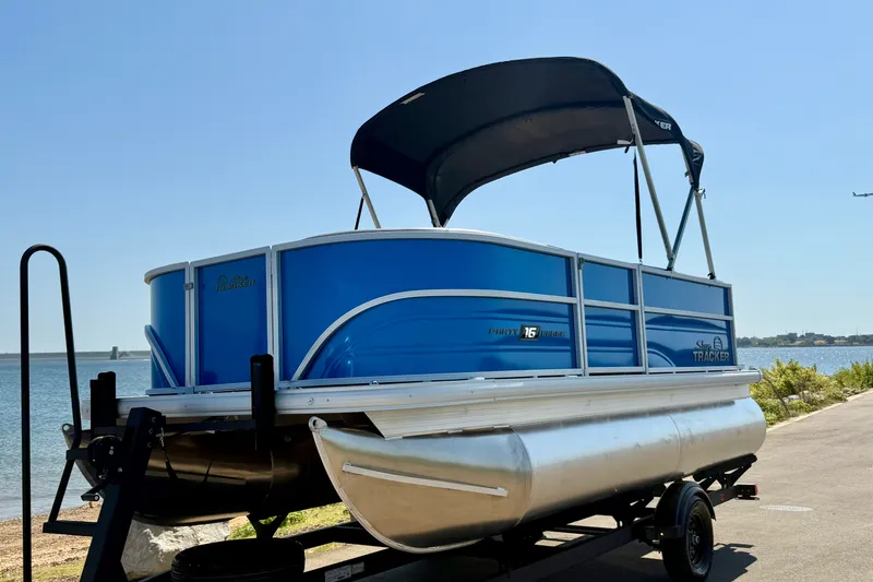 Slide: The Image of 2027 Sun Tracker Party Barge 16 DLX pontoon boat on trailer by the water. - 18