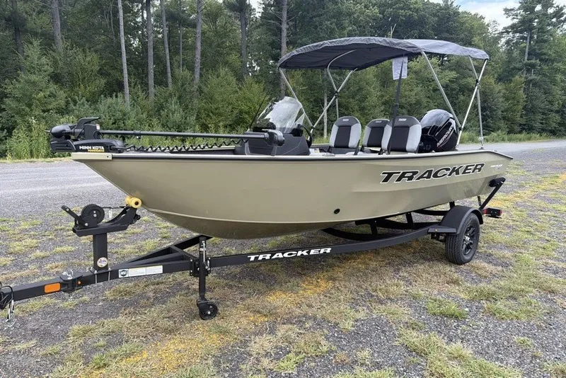 The Image of 2027 Tracker Pro Guide V-16 SC boat on trailer, parked outdoors with canopy. - 0