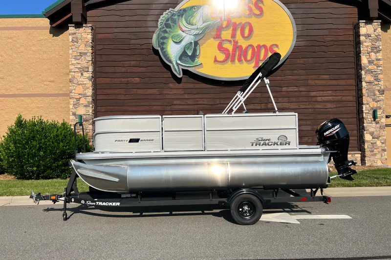 The Image of 2027 Sun Tracker Party Barge 16 DLX pontoon boat on trailer outside Bass Pro Shops. - 0