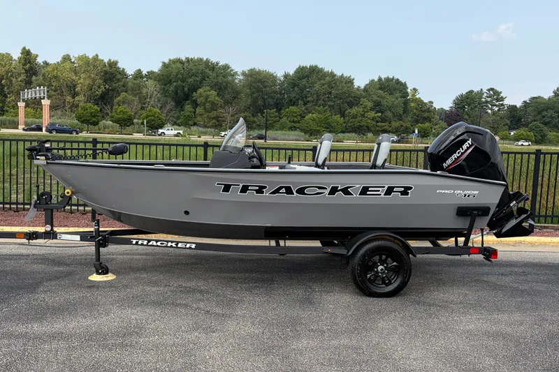 The Image of 2027 Tracker Pro Guide V-16 SC boat on trailer, parked outdoors. - 0