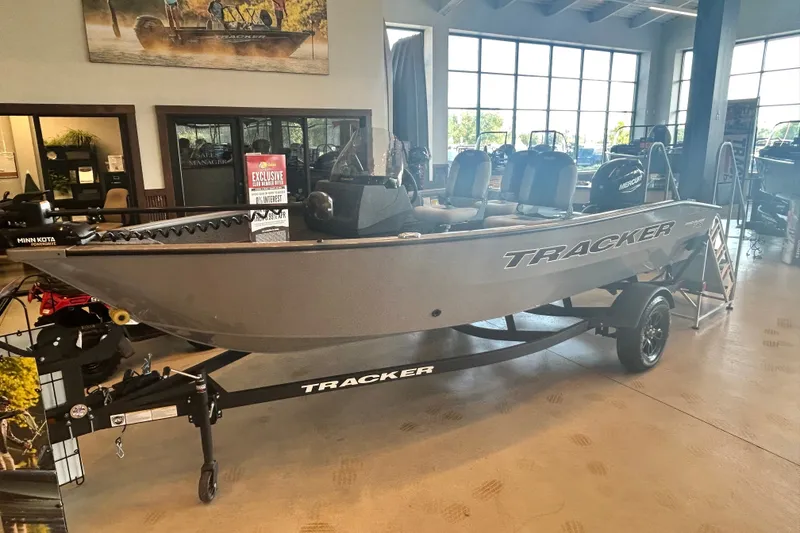 The Image of 2027 Tracker Pro Guide V-16 SC boat displayed in showroom with trailer. - 0