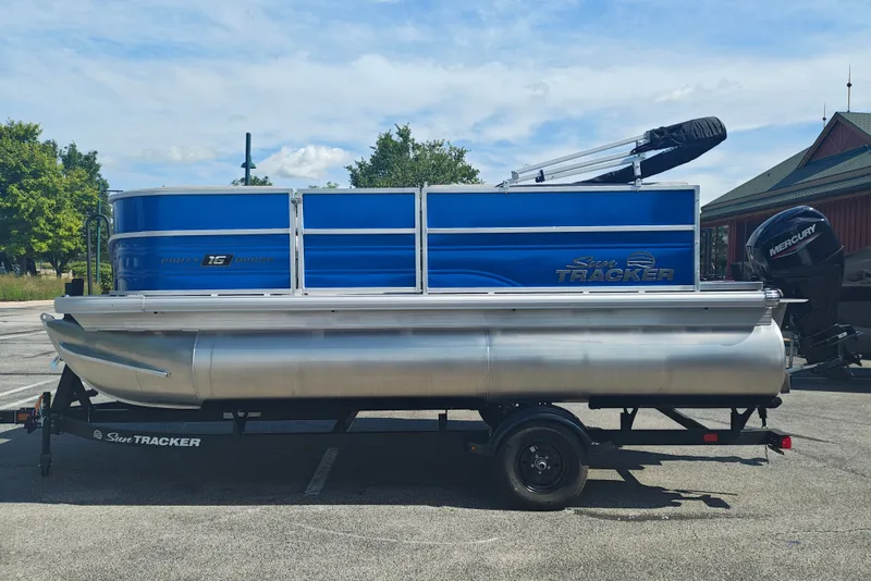 The Image of 2027 Sun Tracker Party Barge 16 DLX pontoon boat on trailer, parked outdoors. - 0