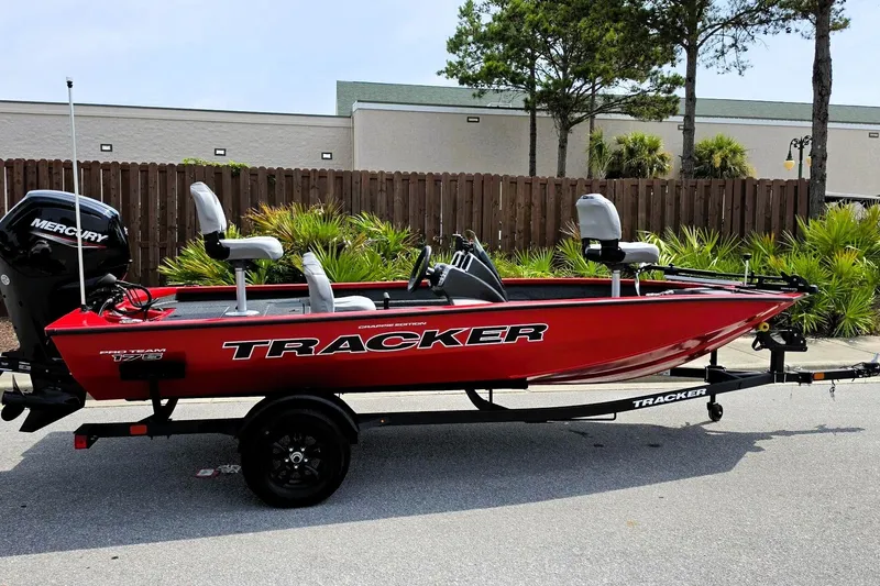 The Image of 2027 Tracker Pro Team 175 Crappie Edition boat, red, on trailer, parked outdoors. - 0