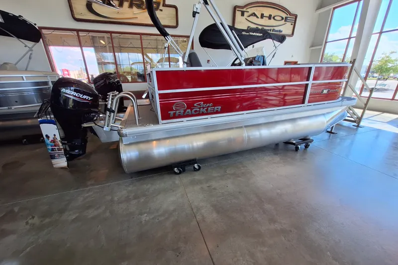 The Image of 2027 Sun Tracker Party Barge 16 DLX pontoon boat displayed indoors with Mercury engine. - 0