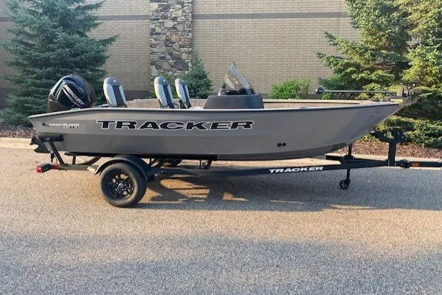 The Image of 2027 Tracker Pro Guide V-16 SC boat on trailer, parked outdoors. - 0