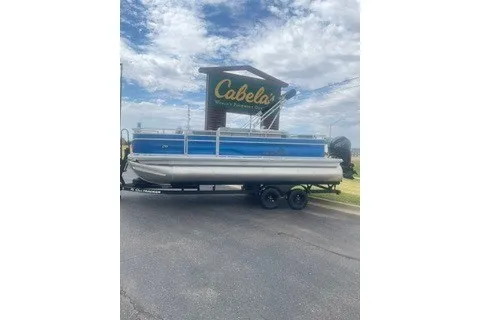The Image of 2027 Sun Tracker Fishin' Barge 20 DLX pontoon boat parked near Cabela's sign. - 0