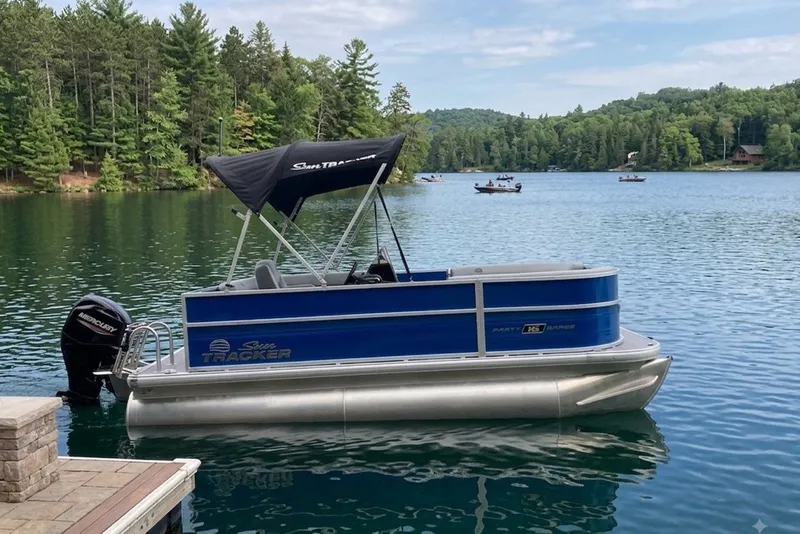 The Image of 2027 Sun Tracker Party Barge 16 DLX pontoon boat on a serene lake. - 0