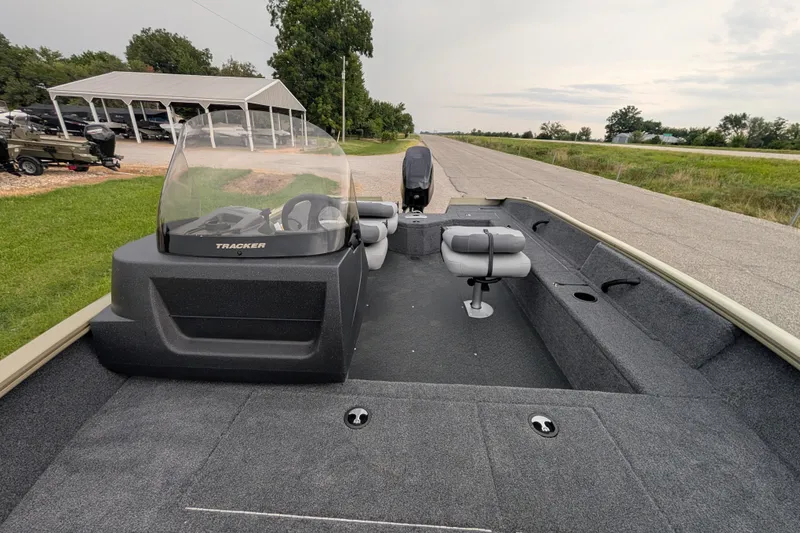 Slide: The Image of 2027 Tracker Pro Guide V-16 SC boat with seating and console, parked outdoors. - 56