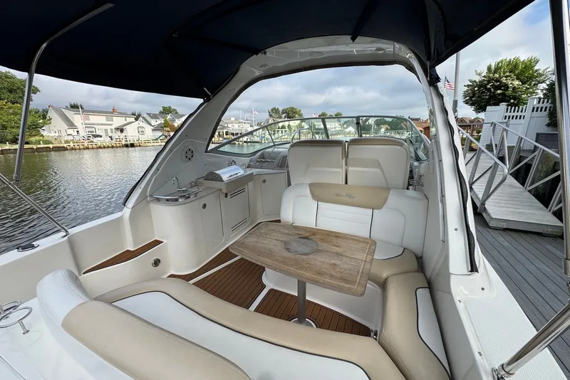 Slide: The Image of 2008 Sea Ray Sundancer 310 interior with seating and table, docked by waterfront homes. - 8