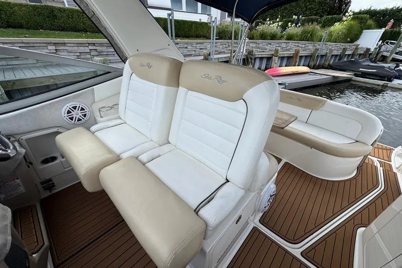 Slide: The Image of 2008 Sea Ray Sundancer 310 interior with beige and white seating, docked by the water. - 13