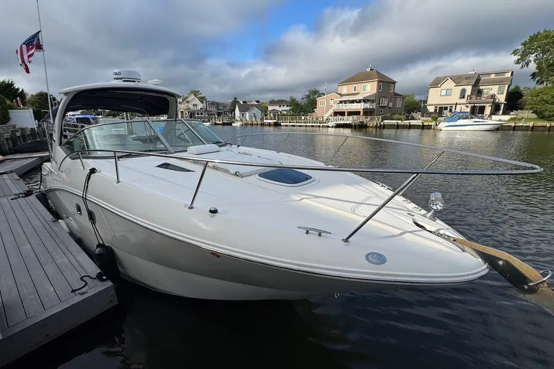 Slide: The Image of 2008 Sea Ray Sundancer 310 docked by waterfront homes under a cloudy sky. - 5