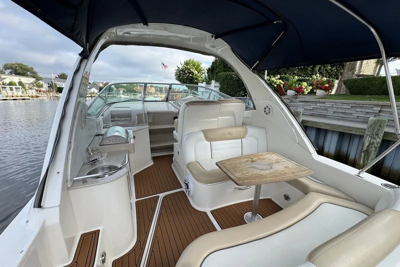Slide: The Image of 2008 Sea Ray Sundancer 310 interior with seating, table, and kitchenette by the water. - 7