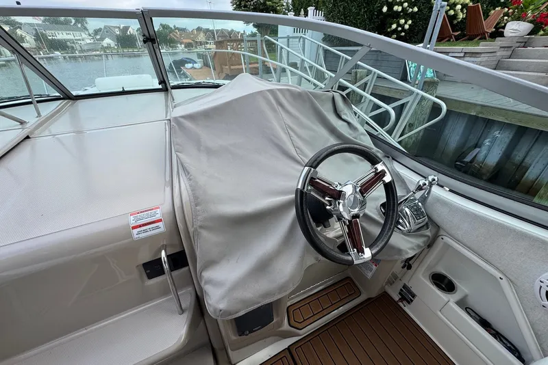 Slide: The Image of 2008 Sea Ray Sundancer 310 cockpit with covered controls and steering wheel. - 15