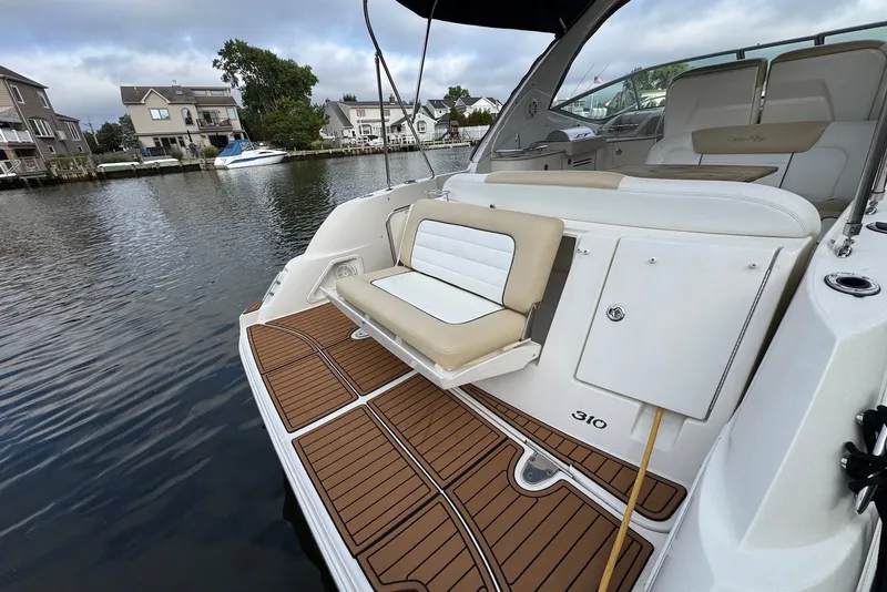 Slide: The Image of 2008 Sea Ray Sundancer 310 yacht with elegant seating, docked by waterfront homes. - 10