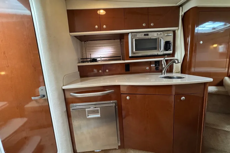 Slide: The Image of 2008 Sea Ray Sundancer 310 interior kitchen with wood cabinetry, sink, microwave, and compact fridge. - 22