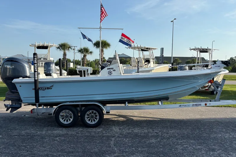 Slide: The Image of 2026 Bulls Bay 2200 XS boat on trailer, displayed outdoors with flags in background. - 3